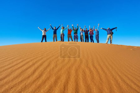 Téléchargez les photos : Un groupe de touristes explore les majestueuses dunes de sable du désert du Sahara au Maroc par une journée ensoleillée - en image libre de droit