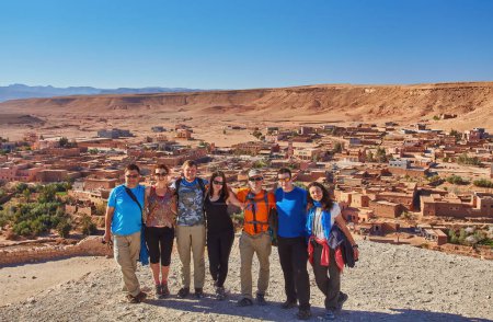 Photo for Tourists capture a shared moment, smiling and posing for a group photo against the historic backdrop of Ait-Ben-Haddou's ancient architecture - Royalty Free Image
