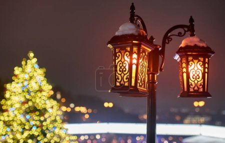Foto de Una antorcha en la calle con luces navideñas por la noche, borrosa de bokeh. Concepto de atmósfera de Año Nuevo. - Imagen libre de derechos