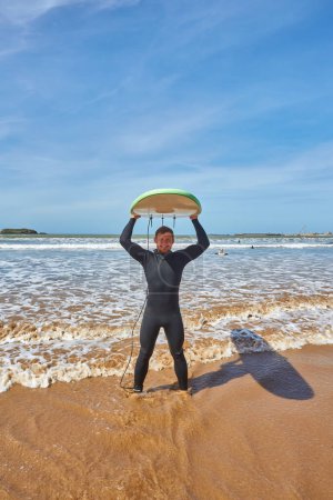 Photo for A young surfer strikes a pose with his board on the oceanfront in Essaouira, capturing the essence of surf culture against the picturesque backdrop of the Atlantic - Royalty Free Image