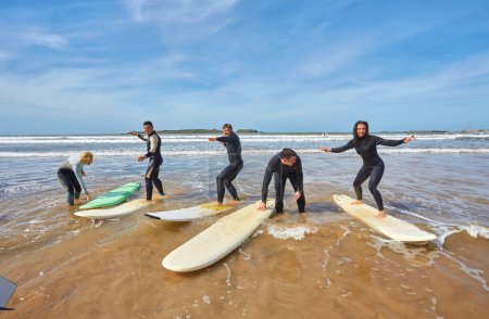 Foto de Un grupo de jóvenes surfistas captura un momento colectivo con sus tablas frente al mar en Essaouira, Marruecos, mostrando la camaradería y la pasión de la vida costera. - Imagen libre de derechos