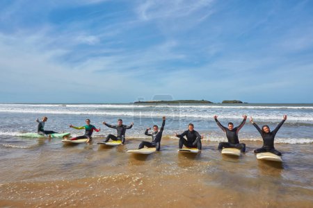Téléchargez les photos : Un groupe de jeunes surfeurs dynamiques saisit un moment collectif avec leurs planches au bord de l'océan à Essaouira, au Maroc. La camaraderie de la culture surf sur fond de charme côtier pittoresque d'Essaouira - en image libre de droit