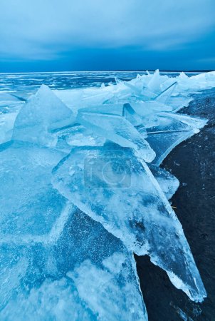 Foto de Una impresionante vista de invierno con una capa de hielo azul cristalino que cubre suavemente la orilla del lago en una impresionante exhibición de belleza natural congelada - Imagen libre de derechos