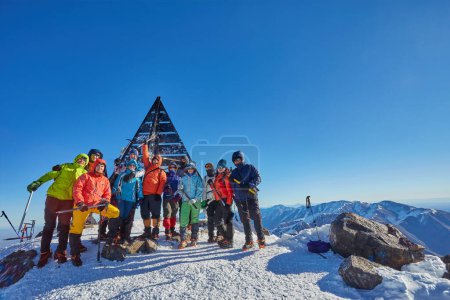 Foto de Un grupo de escaladores capturando el momento en la cumbre del Monte Toubkal, Marruecos, celebrando su triunfo con una fotografía colectiva - Imagen libre de derechos