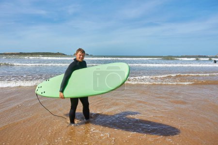 Photo for A young surfer strikes a pose with his board on the oceanfront in Essaouira, capturing the essence of surf culture against the picturesque backdrop of the Atlantic - Royalty Free Image