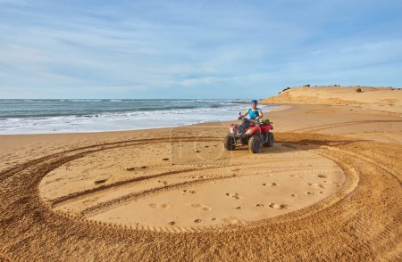 Photo for A young man explores the oceanfront on a quad bike near Essaouira, capturing the thrill of an adventurous ride along the scenic coastal landscape. - Royalty Free Image