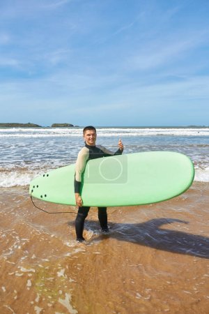 Foto de Un joven surfista posa con su tabla en el frente del mar en Essaouira, capturando la esencia de la cultura del surf contra el pintoresco telón de fondo del Atlántico - Imagen libre de derechos