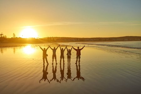 Foto de Los turistas capturan la esencia del amanecer en la playa atlántica de Essaouira, fotografiando recuerdos de siluetas contra el cielo temprano en la mañana.. - Imagen libre de derechos
