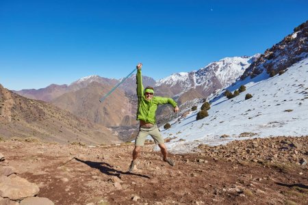 Téléchargez les photos : Un touriste se tient sur le col de l'Atlas, regardant les sommets enneigés, capturant la majesté de cette évasion sereine de montagne. - en image libre de droit