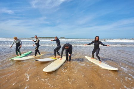Foto de Un grupo de jóvenes surfistas captura un momento colectivo con sus tablas frente al mar en Essaouira, Marruecos, mostrando la camaradería y la pasión de la vida costera. - Imagen libre de derechos