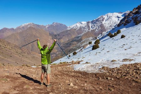 Foto de Un turista se para en el paso de las montañas del Atlas, contemplando picos nevados, capturando la majestuosidad de esta serena escapada de montaña. - Imagen libre de derechos