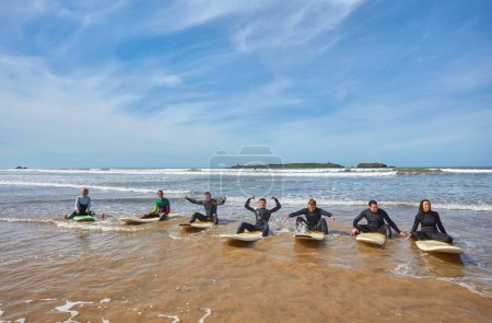 Photo for A group of vibrant young surfers captures a collective moment with their boards on the ocean's edge in Essaouira, Morocco. The camaraderie of surf culture against the backdrop of Essaouira's scenic coastal charm - Royalty Free Image