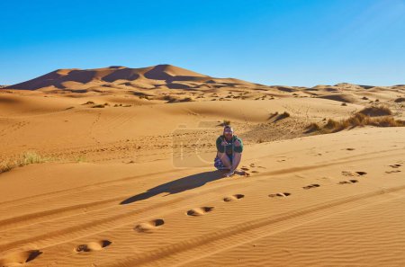Foto de Un viajero solitario en el Sahara, cautivado por la vasta extensión de dunas doradas bajo el sol brillante - Imagen libre de derechos