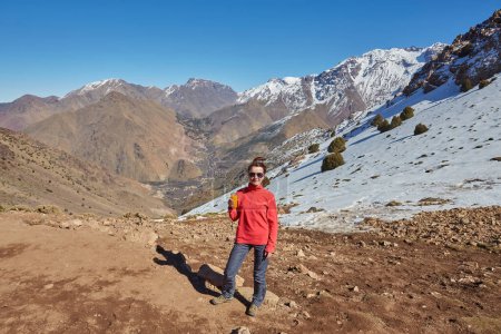 Foto de Un turista en el paso de las montañas del Atlas, con picos nevados detrás, captura la serena belleza del paisaje montañoso. - Imagen libre de derechos