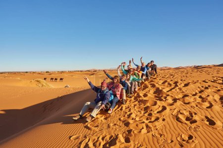Téléchargez les photos : Un groupe de touristes explore les majestueuses dunes de sable du désert du Sahara au Maroc par une journée ensoleillée - en image libre de droit