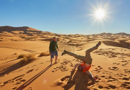 Foto de Un animado grupo de turistas captura momentos en el desierto del Sahara, sorprendentes poses alegres - Imagen libre de derechos