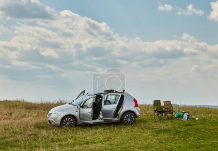 Photo for Picnic in the mountains with folding chairs and a table. The car and the rubber wheel. - Royalty Free Image