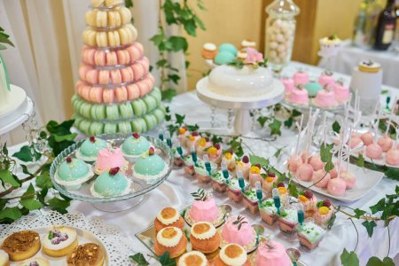 Foto de Torre Macaron o pirámide y cupcakes en mesa de postre dulce - Imagen libre de derechos