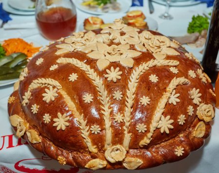 Ukrainian decorated fresh loaf with salt lies on the table, next to the embroidered towel. Ukrainian wedding traditions. Tasty pie.