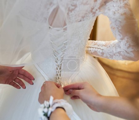 Foto de Dama de honor abotonando el vestido de novia, detalles de hermoso vestido de novia de encaje - Imagen libre de derechos