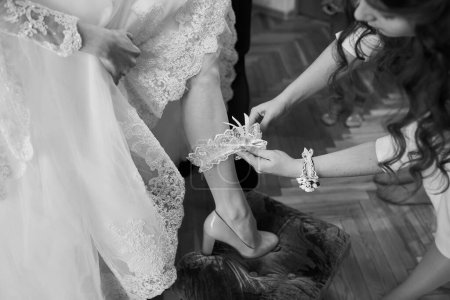 Téléchargez les photos : Demoiselle d'honneur boutonner la robe sur la mariée, détails de belle robe de mariée en dentelle - en image libre de droit