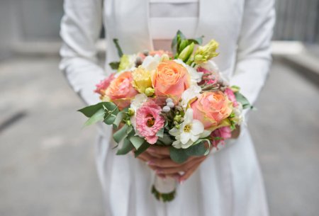 Téléchargez les photos : Mains gracieuses tenant le bouquet d'une mariée, mettant en valeur la beauté des fleurs de mariage. - en image libre de droit