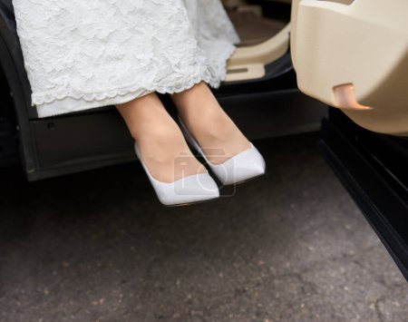 Foto de Novia con vestido de novia blanco y zapatos. Zapatos blancos en los pies de la novia. Hermosas piernas de la novia vestida con zapatos. - Imagen libre de derechos