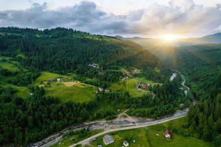 Malerische Luftaufnahme der nebligen Karpaten, Dorf und blauer Himmel mit Sonne und Wolken im Morgenlicht, Sommer ländliche Landschaft, Outdoor-Reisehintergrund
