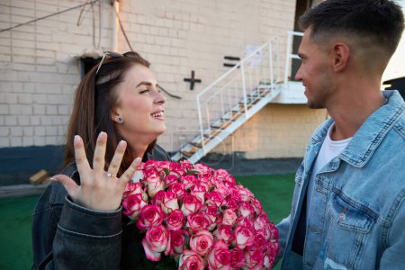 Téléchargez les photos : Un jeune homme propose un grand geste, en présentant un grand bouquet de roses à sa bien-aimée. Le moment est rempli d'amour, d'anticipation et de promesse d'un avenir partagé. - en image libre de droit