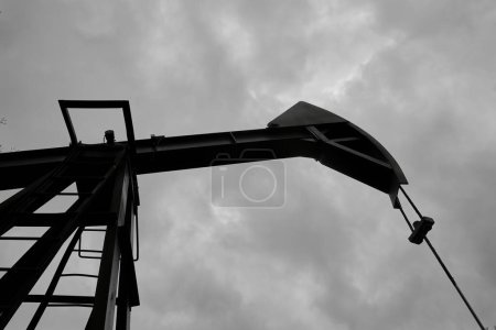 Téléchargez les photos : An abandoned oil or gas rocking machine against a blue sky, exhausted resource. A clogged field of gas and oil production. - en image libre de droit