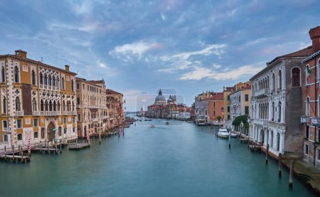 Foto de Antiguo canal con puente, góndola, casas, flores en tiempo nublado.Venecia Italia - Imagen libre de derechos