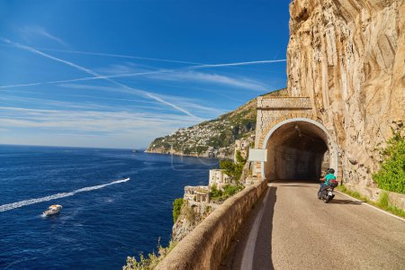 Foto de Scooter conduce por la carretera a lo largo de la costa de Amalfi, acercándose al túnel Conca dei Marini, Italia - Imagen libre de derechos