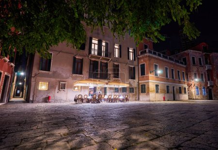 Téléchargez les photos : Vue de nuit de Venise un couple assis sous le feu de la rue à côté d'un pont - en image libre de droit