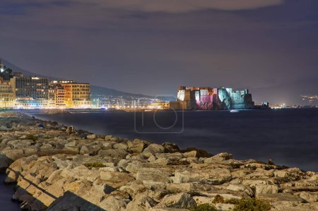 Castel dell Ovo Egg castillo en Nápoles, Italia, vista desde el muelle de la playa en la luz azul de la noche