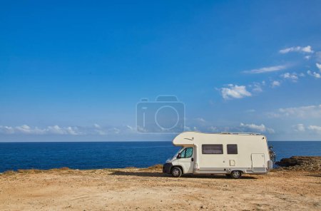 Camper rv caravan on mediterranean coast in Italy. Wild camping on sea shore. Holidays and travel in motor home.