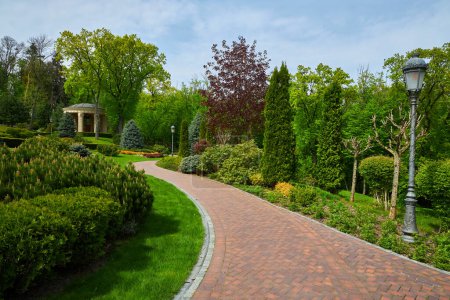 der Hinterhof des Gebäudes mit Stufen und Eingang, vor dem Sträucher immergrüner Baumarten in quadratischer Form wachsen, Fußweg aus Ziegeln um ein Labyrinth von Baumarten.
