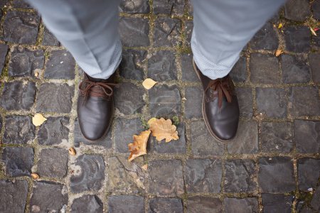 Foto de Zapatos de hombre, zapatos para el novio, botas y pantalones, el hombre se para en la losa de pavimentación, en el suelo - Imagen libre de derechos