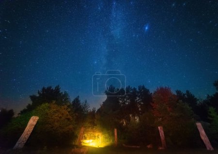 Un cliché nocturne impressionnant capturant une tente jaune illuminée de l'intérieur, et la Voie lactée impressionnante et les étoiles dans le ciel nocturne sombre.