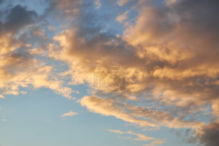 Un fragment d'un ciel brillant au coucher du soleil avec des nuages bizarrement formés. Ciel crépusculaire captivant affichant une palette de teintes chaudes, parfait pour vos projets de conception.
