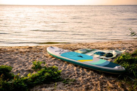 Téléchargez les photos : Planche à pagaie sur la côte du lac au coucher du soleil - en image libre de droit