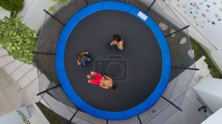 Photo for Children playing on trampoline aerial view together - Royalty Free Image
