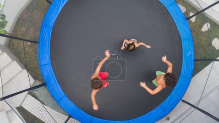 Téléchargez les photos : Enfants jouant sur le trampoline vue aérienne ensemble - en image libre de droit
