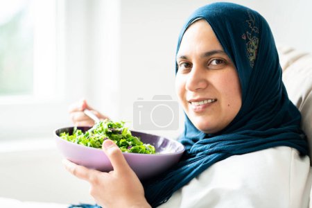 Téléchargez les photos : Femme musulmane avec hijab manger sa salade verte seule - en image libre de droit