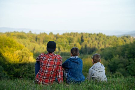 Téléchargez les photos : Petits garçons sur une prairie verte regardant au loin la forêt. Photo de haute qualité - en image libre de droit