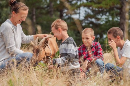 Téléchargez les photos : Enfants sur le terrain agricole rural jouant avec les chèvres de la ferme. Photo de haute qualité - en image libre de droit