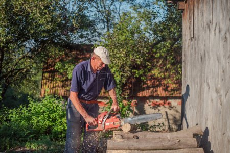 Foto de Hombre mayor cortando árbol con motosierra en el jardín. Foto de alta calidad - Imagen libre de derechos