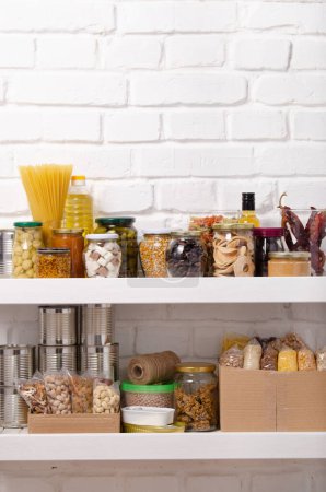 Set of long storage term foods on pantry shelf prepared for disaster emergency conditions on brick wall background