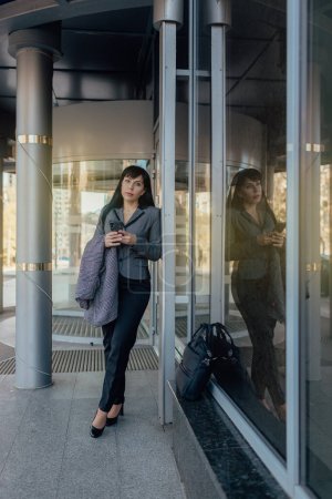 Photo for Confident businesswoman in casual clothes and with a laptop on the background of the business center. The concept of working on the Internet - Royalty Free Image