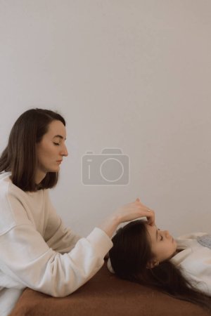 Kinder Energie Massage entspannende und pflegende Behandlung für Körper und Achtsamkeit Gesundheit sanfte Frauenarme mit Kopf tun Zugangsstangen und Gesicht junge Prozedur. Energetische Massage nimmt die Energiezirkulation im Körper wieder auf.