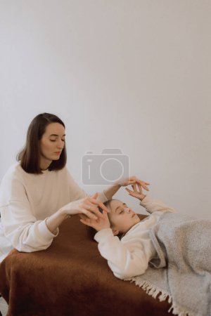 Kids energy massage relaxing and care treatment for body and mindfull health gentle woman arms holding head doing access bars and face young procedure. Energetic massage resumes the circulation of energy in body.